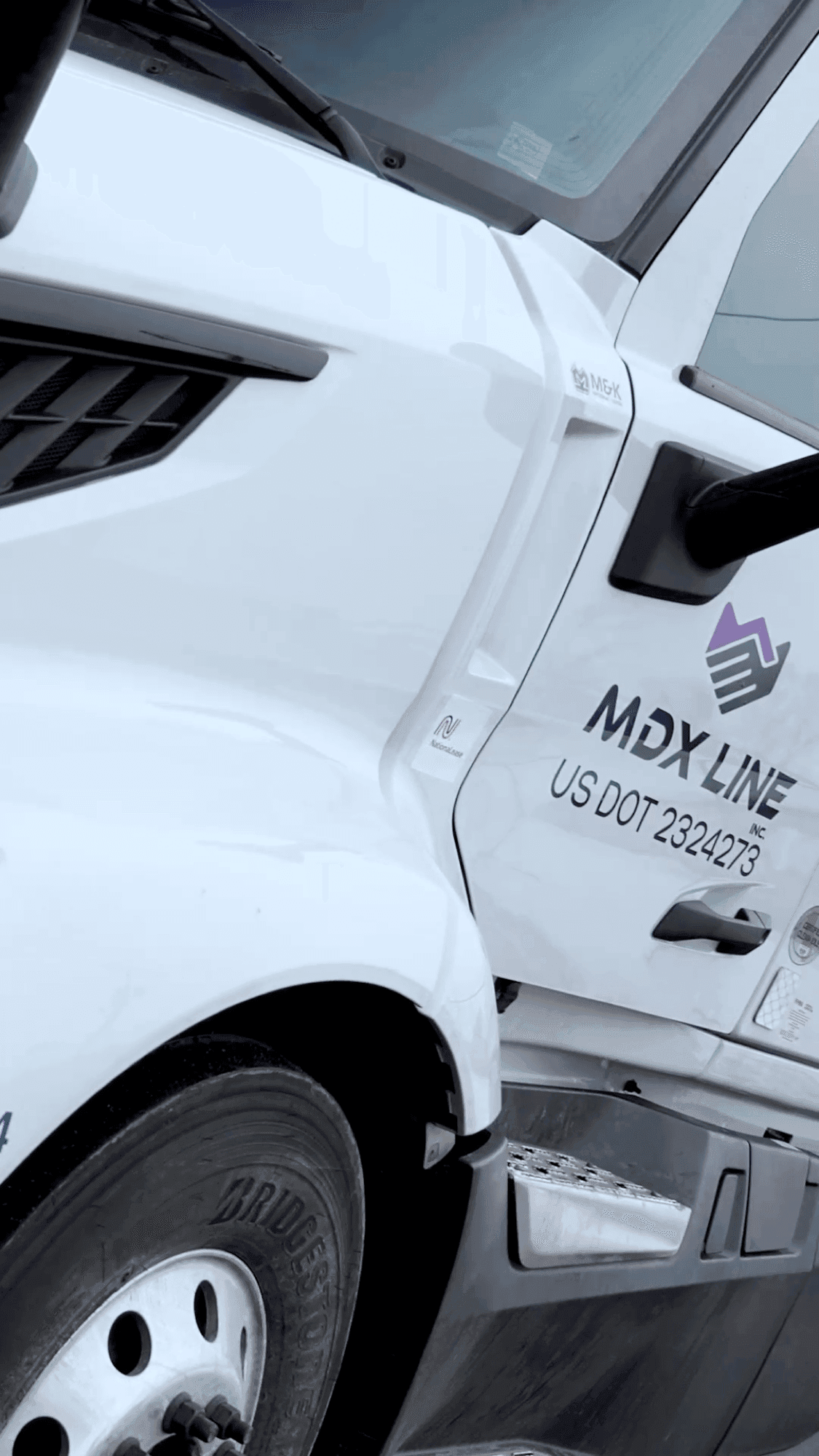 Close-up of MDX Line branded truck door with logo and DOT number